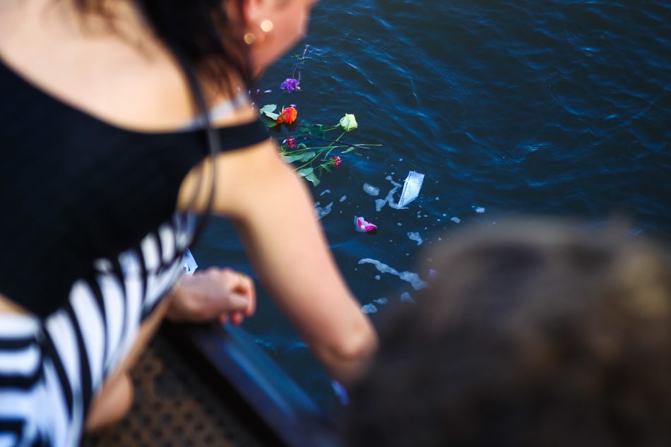 Teilnehmer der Seebrücke lassen Blumen und symbolische Papierboote in die Elbe