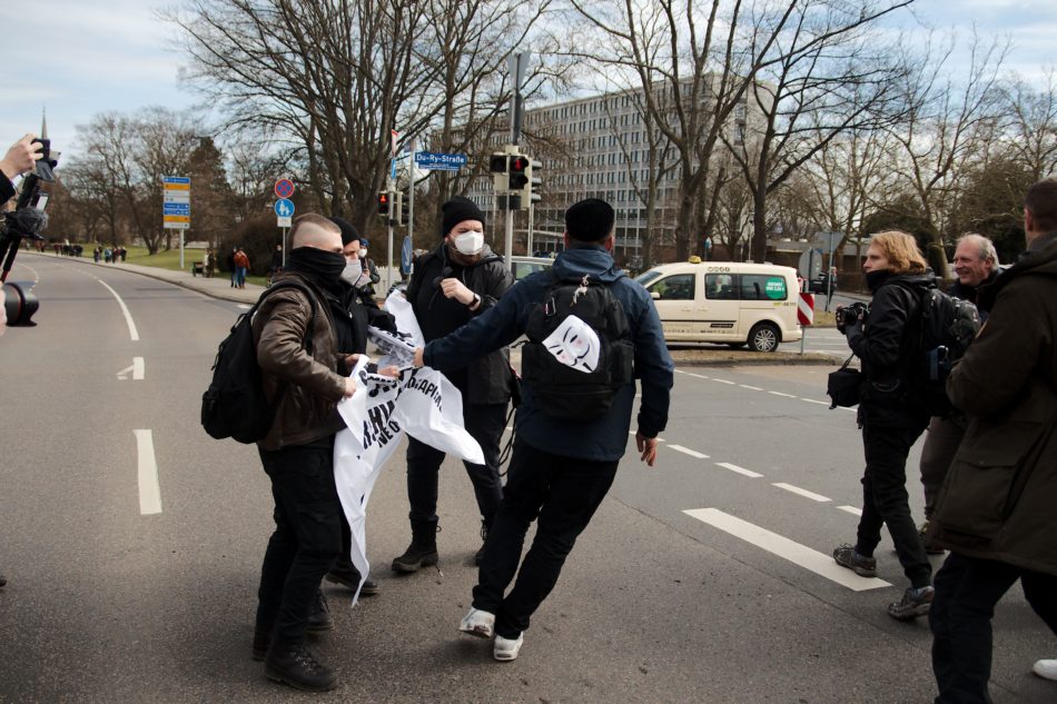 Ein "Querdenker" versucht den beiden Gegendemonstranten ihr Transparent zu entreißen