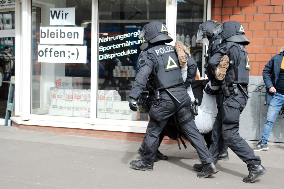 Ein Person wird von Polizisten weg getragen