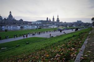 Menschen stehen mit Schildern in der Hand in einer Reihe. Im Hintergrund sieht man die Dresdner Altstadt