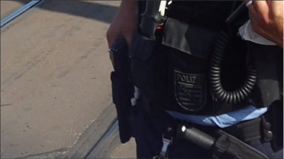 Ein Dresdner Polizist "Sichert" seine Dienstwaffe bei einer Demonstration